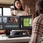 Colleagues discussing video editing project at desk