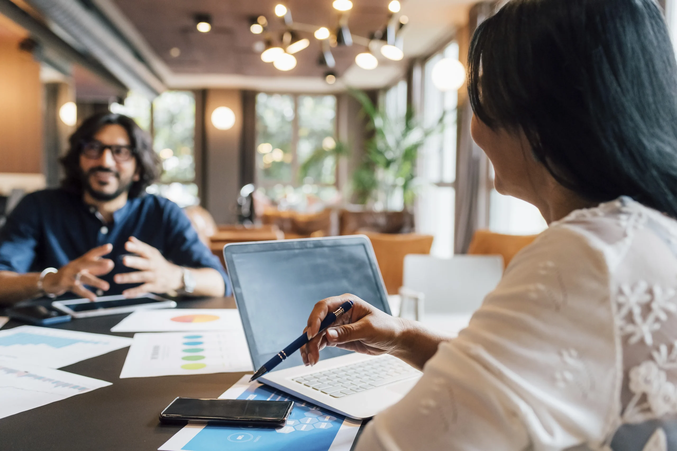 Colleagues discussing business strategy with laptop and charts